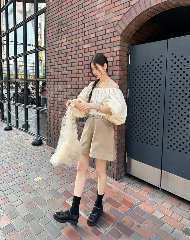 Quần short vải màu be thoạt nhìn khá đơn điệu song khi mix cùng áo blouse trễ vai điệu đà